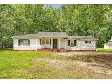 Charming single-story home featuring a covered front porch, black shutters, and mature trees at 2202 Sc-61, Ridgeville, SC 29472