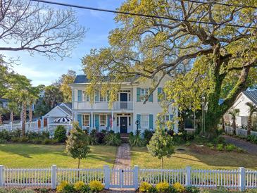 Charming two-story home with a brick walkway, white picket fence, and lush landscaping at 304 Bank St, Mount Pleasant, SC 29464