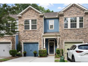 Charming townhome with stone facade, blue accents, two-car garage, and manicured landscaping at 826 Bibury Ct, Charleston, SC 29414