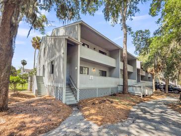 Multi-story condo building features updated exterior paint, white trim and balconies overlooking mature trees at 291 Sea Cloud Cir, Edisto Beach, SC 29438