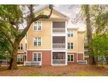 Three-story condo building featuring private screened balconies and views of lush landscaping and mature trees at 300 Bucksley Ln # 102, Charleston, SC 29492