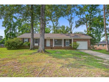 Charming single-story brick home featuring a manicured lawn, mature trees, and a cozy front porch at 127 Cornell Dr, Ladson, SC 29456