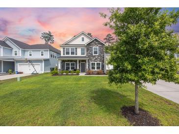 Charming two-story home featuring stone accents, a well-manicured lawn, and a cozy front porch at 223 Granton Edge Ln, Summerville, SC 29486
