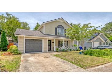 Charming two-story home featuring a cozy front porch, attached garage, and well-maintained lawn at 1743 Orange Grove Shores Dr, Charleston, SC 29407