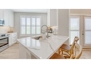 Modern kitchen featuring a marble countertop island with seating and bright white cabinets at 260 Seven Farms Dr # 306, Charleston, SC 29492