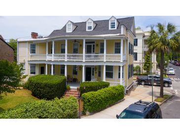 Charming yellow two-story home featuring a double veranda and manicured landscaping at 29 Smith St, Charleston, SC 29401