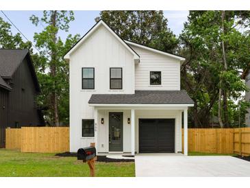 Charming two-story home features a modern design with a black garage door and a well-maintained front yard at St, Charleston, SC 29407