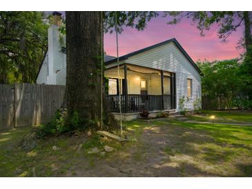 Charming exterior of the house featuring a porch, swing, and well-lit landscape at dusk at 1248 Sumner Ave, North Charleston, SC 29406