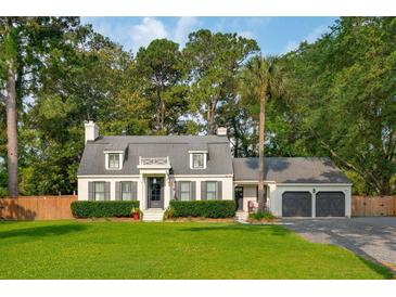 Charming home with a manicured lawn, dark shutters, and a brick paver driveway leading to the attached garage at 1446 Burningtree Rd, Charleston, SC 29412