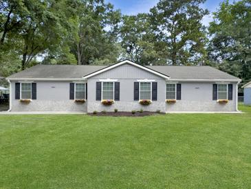 Charming single-story home with a well-manicured lawn, flower boxes and manicured garden at 2174 Eleanor Dr, North Charleston, SC 29406