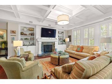 Bright living room featuring a coffered ceiling, fireplace, built-in shelving, and plantation shutters at 6002 Green Dolphin Way, Kiawah Island, SC 29455