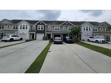 View of townhomes with individual garages and driveways, with tasteful neutral exterior colors, and well-manicured landscaping at 9712 Transplanter Cir, Ladson, SC 29456