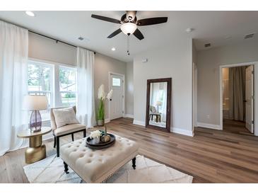 Bright living room featuring wood floors, a ceiling fan, and a large window with white curtains at St, Saint George, SC 29477