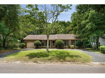 Charming brick home featuring a well-manicured lawn, mature tree, and a welcoming front porch at 1002 Sea Gull Dr, Mount Pleasant, SC 29464