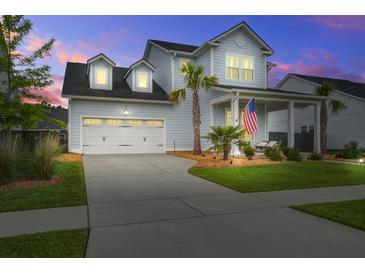 Charming two-story home with a manicured lawn, covered porch, and attached two-car garage at dusk at 111 Medford St, Summerville, SC 29486