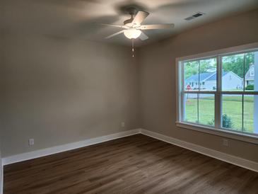 Bright bedroom features hardwood floors, ceiling fan, and a large window with natural light at 1207 Albert Storm Ave, Moncks Corner, SC 29461