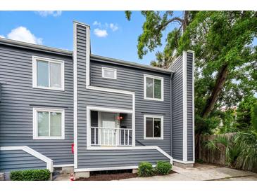 Charming gray two-story home with a small porch and lush green landscaping under a blue sky at 22 Ogier St, Charleston, SC 29403