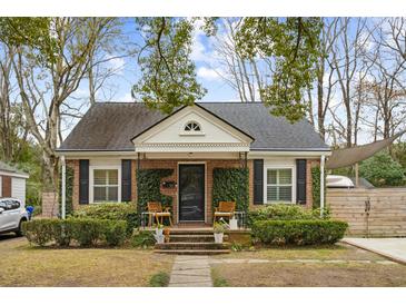 Charming brick home featuring black shutters, mature landscaping, and inviting front porch with seating at 38 Colleton Dr, Charleston, SC 29407