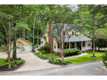 Charming two-story yellow home with a brick chimney, attached garage and a wraparound front porch at 127 White Pine Way, Summerville, SC 29485