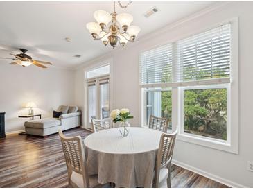 Bright dining area features hardwood floors, a chandelier, and a beautiful view from the large windows at 130 River Landing Dr # 8203, Charleston, SC 29492