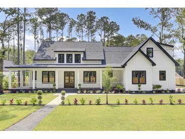 Beautiful modern farmhouse exterior with a lush green lawn and inviting front porch at 142 Argosy Dr, Summerville, SC 29483