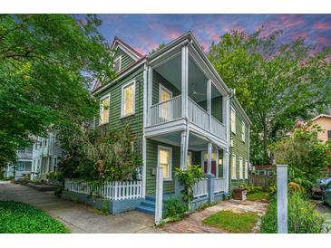 Charming two-story home with double porches and white picket fence, surrounded by lush greenery at 173 Fishburne St, Charleston, SC 29403