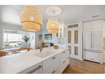 Bright kitchen with white cabinets, brass hardware, and rattan pendant lighting and an island with a breakfast bar at 1815 Long Bend Dr, Seabrook Island, SC 29455