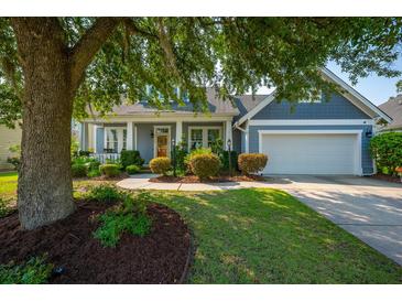 Charming home featuring a manicured front lawn, tree, and a welcoming facade with covered porch and attached garage at 185 Red Leaf Blvd, Moncks Corner, SC 29461