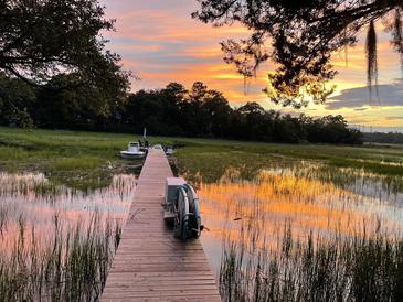 Picturesque dock view at sunset with reflection of the sunset in the water creating a serene and inviting atmosphere at 630 Cain Dr, Mount Pleasant, SC 29464