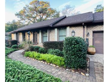Charming brick home with meticulously landscaped front yard, winding walkway, and lush greenery at 1039 Grand Concourse St, Charleston, SC 29412