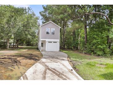 Two-story home with gray siding, white trim, attached garage, and a concrete driveway surrounded by lush greenery at 110 Farm Rd # A, Goose Creek, SC 29445
