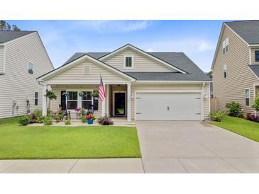 Charming single-story home with a well-manicured lawn, attached two-car garage, and quaint porch at 135 Cypress Preserve Blvd, Moncks Corner, SC 29461