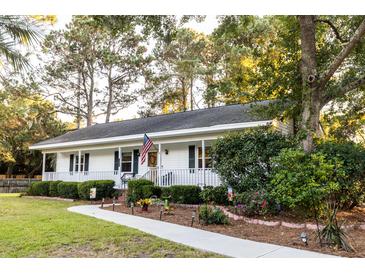 Charming single-story home with a well-manicured lawn, inviting walkway, and an American flag at 1351 Winifred St, Mount Pleasant, SC 29464