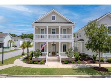 Charming two-story home featuring a double porch, lush landscaping, and an American flag at 1535 Low Pk St, Mount Pleasant, SC 29464