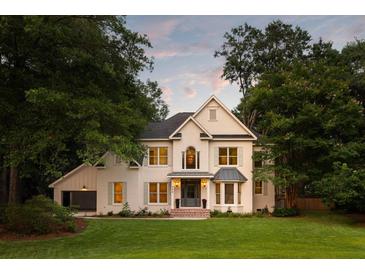 Beautiful two-story white brick home featuring a well-manicured lawn, large trees, and eye-catching architectural details at 499 Lackland Ct, Mount Pleasant, SC 29464