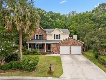 Inviting two-story home with brick facade, front porch, manicured lawn, and two-car garage at 5488 Altamaha Dr, North Charleston, SC 29420