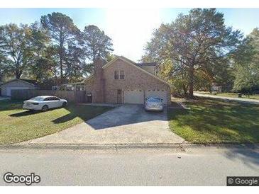 Charming two-story brick home featuring an attached two-car garage and a well-maintained front lawn at 8194 Courtwood Rd, North Charleston, SC 29406