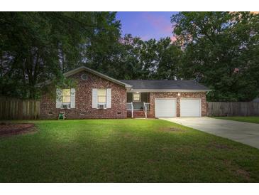Charming brick home featuring a two-car garage, well-manicured lawn, and mature trees at dusk at 110 Terry Ave, Summerville, SC 29485