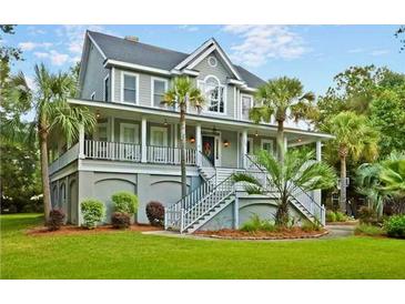 Charming two-story home with a wrap around porch, staircase entry, and lush, green landscaped yard at 1447 Headquarters Plantation Dr, Johns Island, SC 29455