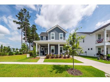 Charming two-story home featuring a covered front porch, well-manicured lawn, and beautiful landscaping at 290 Woodland Oak Way, Summerville, SC 29485