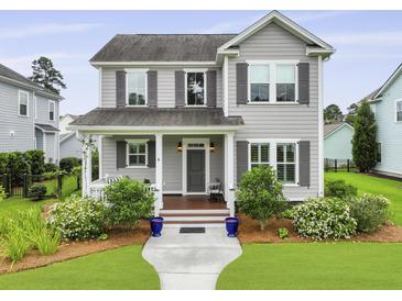 Charming two-story home with gray siding, shuttered windows, manicured lawn and a welcoming front porch with tasteful decor at 3998 Capensis Ln, Ravenel, SC 29470