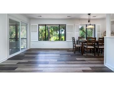 Sunlit dining area featuring wood floors, neutral walls, and large windows with views at 855 Club Cottage Rd, Edisto Island, SC 29438