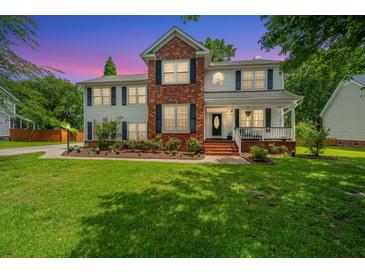 Charming two-story home with a lush green lawn and colorful flowerbeds at dusk at 2026 Thornhill Dr, Summerville, SC 29485
