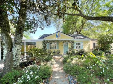 Charming yellow home featuring lush landscaping, a quaint garden path, and a cozy sitting area on the front porch at 2149 Stonewood Dr, Charleston, SC 29412