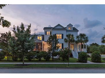 Charming two-story white home with lush landscaping, black iron fence, and a welcoming front porch at 2489 Daniel Island Dr, Daniel Island, SC 29492