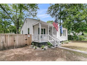 Charming home showcasing a cozy front porch, complemented by a manicured landscape and fresh, white paint at 2666 Poplin Ave, North Charleston, SC 29405