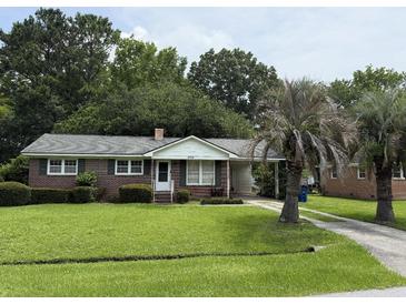 Charming one story brick home with mature landscaping, green lawn, and a paved driveway at 2734 Mona Ave, Charleston, SC 29414