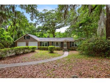 Charming single-story brick home with a two-car garage surrounded by mature trees and a welcoming front walkway at 4822 Parker Dr, North Charleston, SC 29405