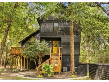 Charming two-story home with a wooden porch and yellow door nestled among mature trees at 6464 Saint Anthony Dr, Meggett, SC 29449
