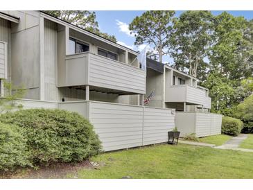 A charming two-story home with a fenced yard, mature trees, and gray wood plank siding at 103 Greencastle Dr, Goose Creek, SC 29445